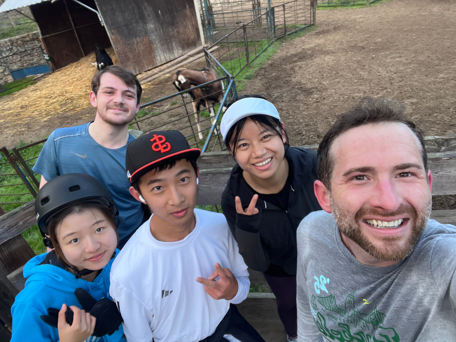 Five members posing for a selfie at Tilden Little Farm with a cow and goat in the background
