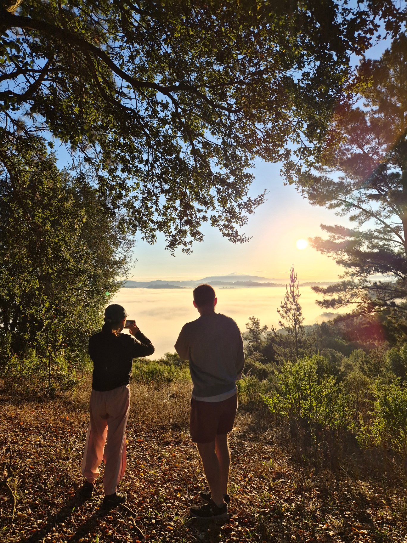 Two members watching the sunrise over a sea of clouds from Inspiration Point