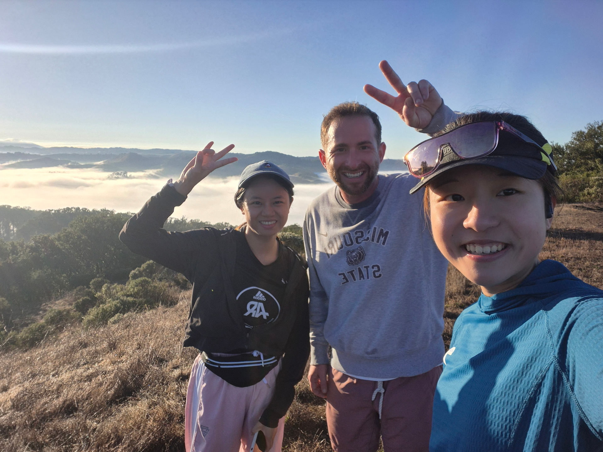 Three members on the Nimitz Trail at Inspiration Point above a sea of clouds